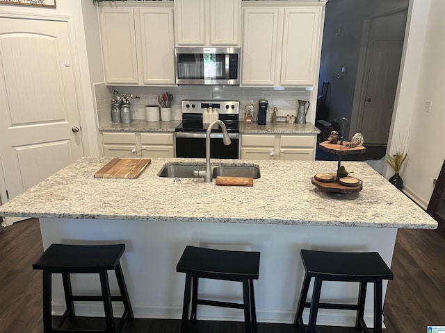 kitchen with appliances with stainless steel finishes, a breakfast bar area, and white cabinets