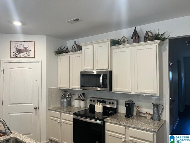 kitchen with white cabinetry, stainless steel appliances, and tasteful backsplash