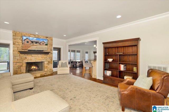 living room with ornamental molding, wood-type flooring, a fireplace, and plenty of natural light