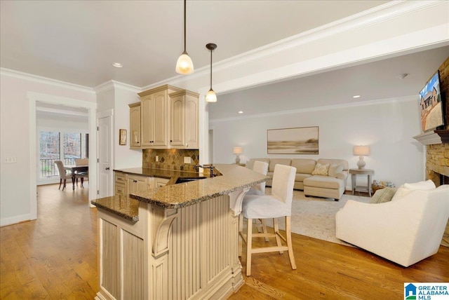 kitchen featuring a breakfast bar, pendant lighting, sink, light hardwood / wood-style floors, and kitchen peninsula