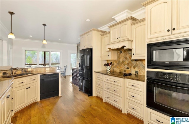 kitchen featuring sink, tasteful backsplash, dark stone countertops, pendant lighting, and black appliances