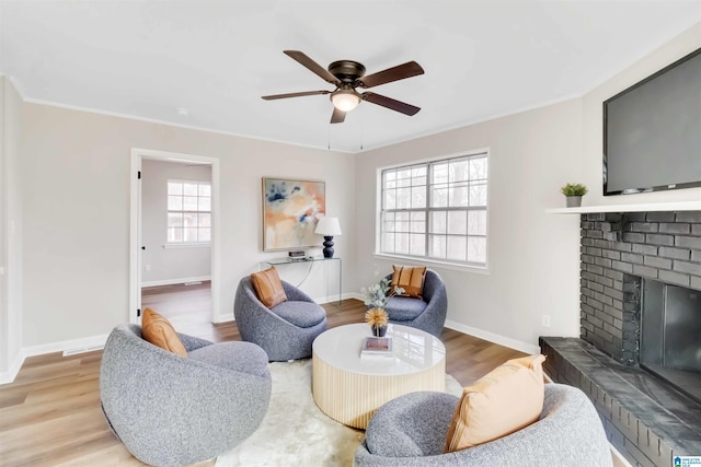 living room with ceiling fan, ornamental molding, light hardwood / wood-style floors, and a brick fireplace