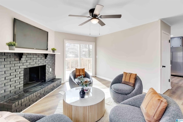 living room featuring wood-type flooring, ceiling fan, and a fireplace