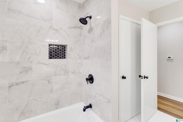 bathroom with tiled shower / bath combo and hardwood / wood-style floors