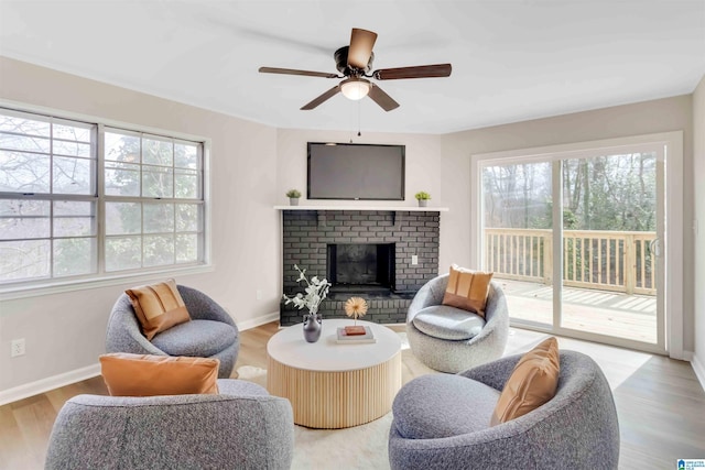 living room featuring ceiling fan, a fireplace, and light wood-type flooring