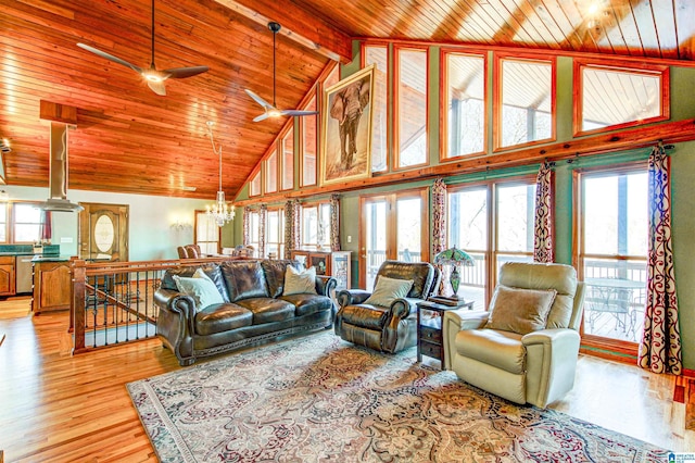 living room featuring ceiling fan with notable chandelier, high vaulted ceiling, light wood-type flooring, wooden ceiling, and beam ceiling