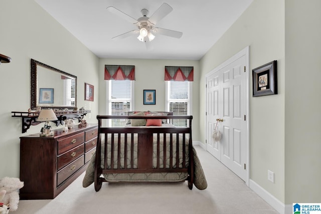 bedroom with ceiling fan, light colored carpet, and a closet