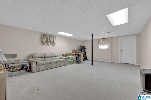 carpeted living room featuring heating unit and a drop ceiling