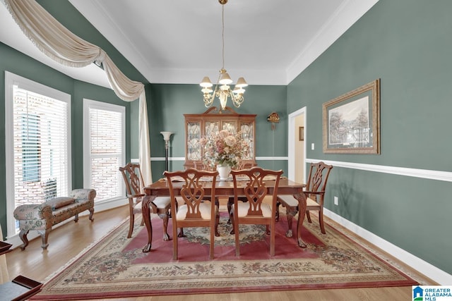 dining space with hardwood / wood-style flooring, ornamental molding, and an inviting chandelier