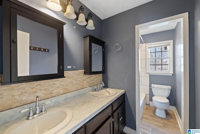 full bathroom with hardwood / wood-style floors, backsplash, vanity, toilet, and a textured ceiling