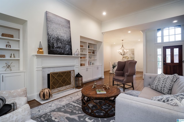 living room featuring crown molding, a chandelier, hardwood / wood-style floors, and built in features