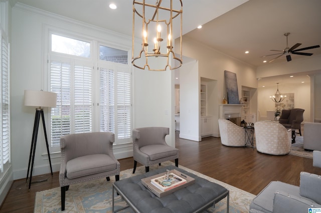 living room with crown molding, dark hardwood / wood-style floors, ceiling fan with notable chandelier, and built in shelves