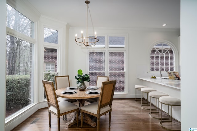 dining area featuring ornamental molding, a healthy amount of sunlight, and a chandelier