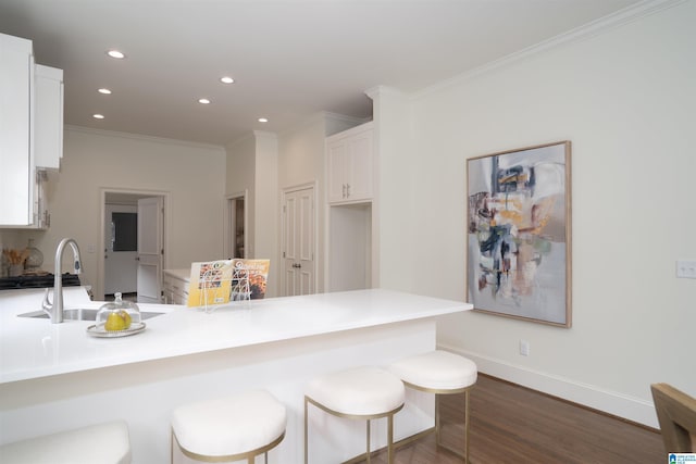 kitchen with sink, white cabinetry, a kitchen bar, dark hardwood / wood-style flooring, and kitchen peninsula