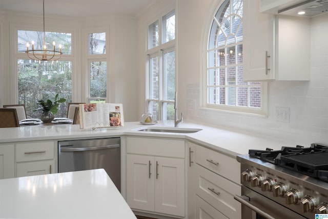 kitchen featuring white cabinetry, sink, decorative backsplash, hanging light fixtures, and stainless steel appliances