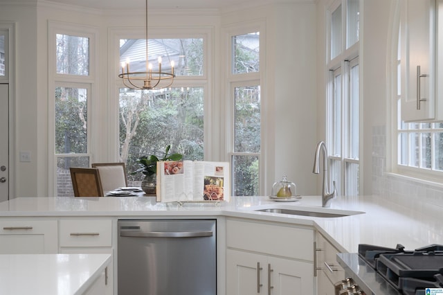 kitchen featuring pendant lighting, sink, white cabinets, stainless steel dishwasher, and an inviting chandelier