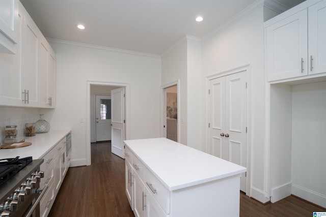 kitchen featuring ornamental molding, stainless steel stove, dark wood-type flooring, and white cabinets