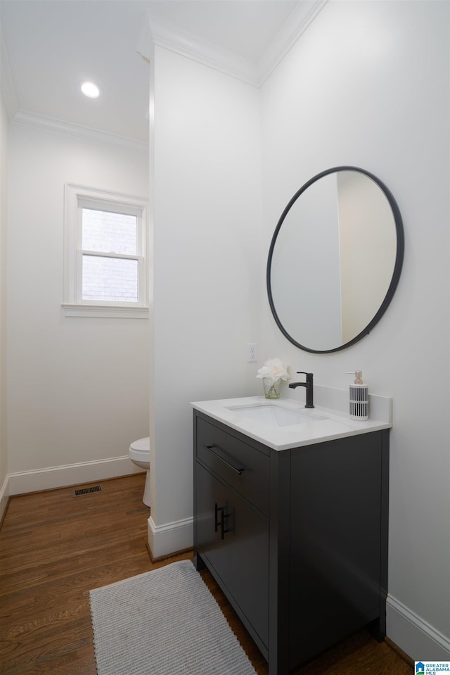 bathroom with vanity, wood-type flooring, ornamental molding, and toilet