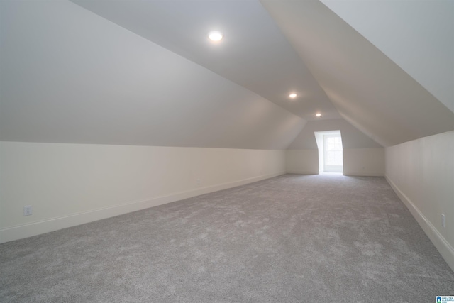 additional living space featuring vaulted ceiling and light carpet