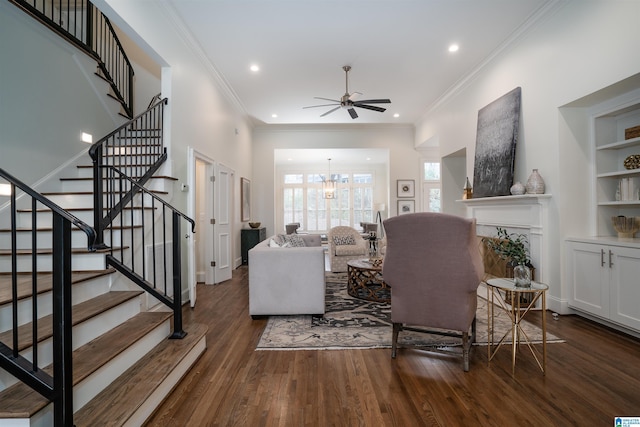 living room featuring dark wood-type flooring, ornamental molding, and ceiling fan with notable chandelier