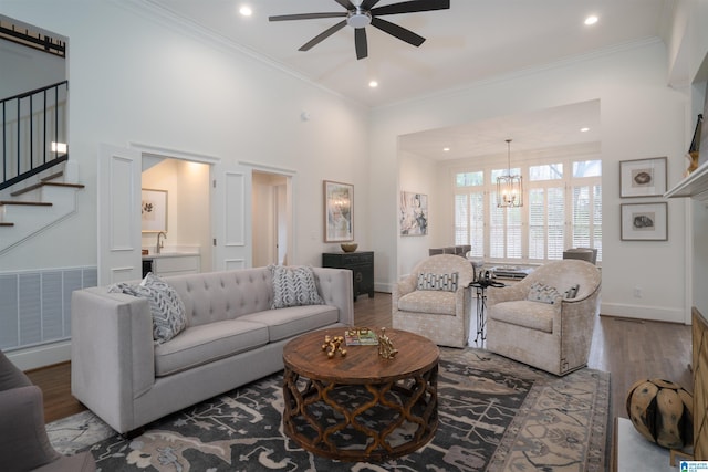 living room featuring ornamental molding, ceiling fan with notable chandelier, sink, and hardwood / wood-style floors