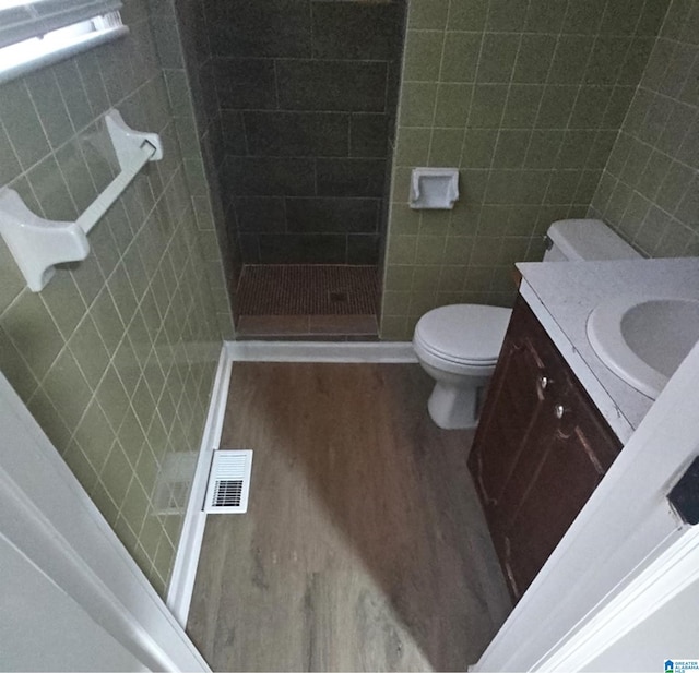 bathroom featuring vanity, toilet, tile walls, and a shower