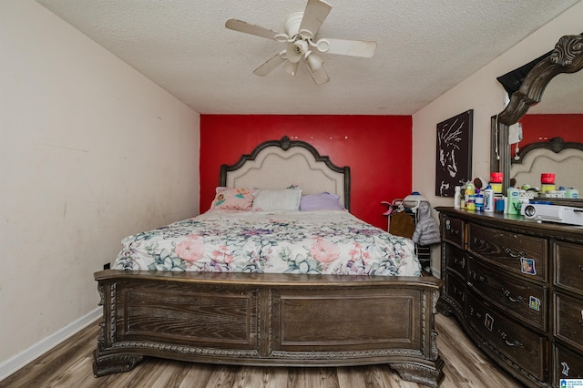 bedroom with ceiling fan, hardwood / wood-style flooring, and a textured ceiling