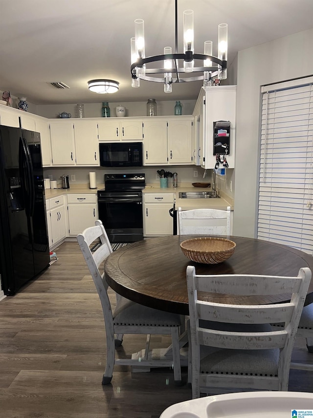 dining room with white cabinetry, hanging light fixtures, dark hardwood / wood-style floors, and sink