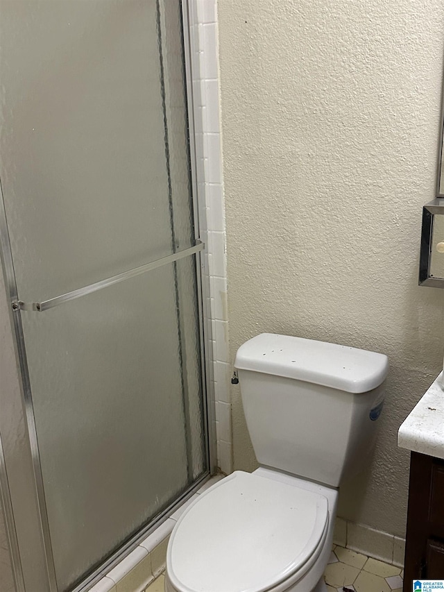 bathroom with vanity, tile patterned floors, a shower with door, and toilet