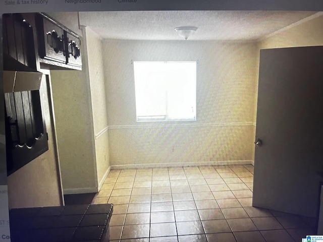 tiled empty room featuring a textured ceiling