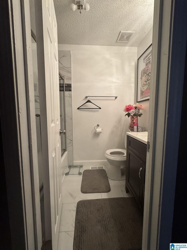 full bathroom featuring vanity, bath / shower combo with glass door, toilet, and a textured ceiling