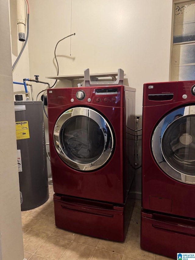 washroom featuring water heater, washer and dryer, and light tile patterned floors