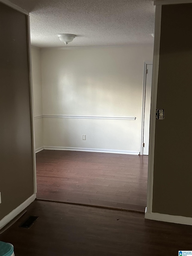 spare room with dark hardwood / wood-style flooring and a textured ceiling