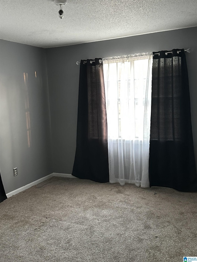 carpeted empty room with a textured ceiling