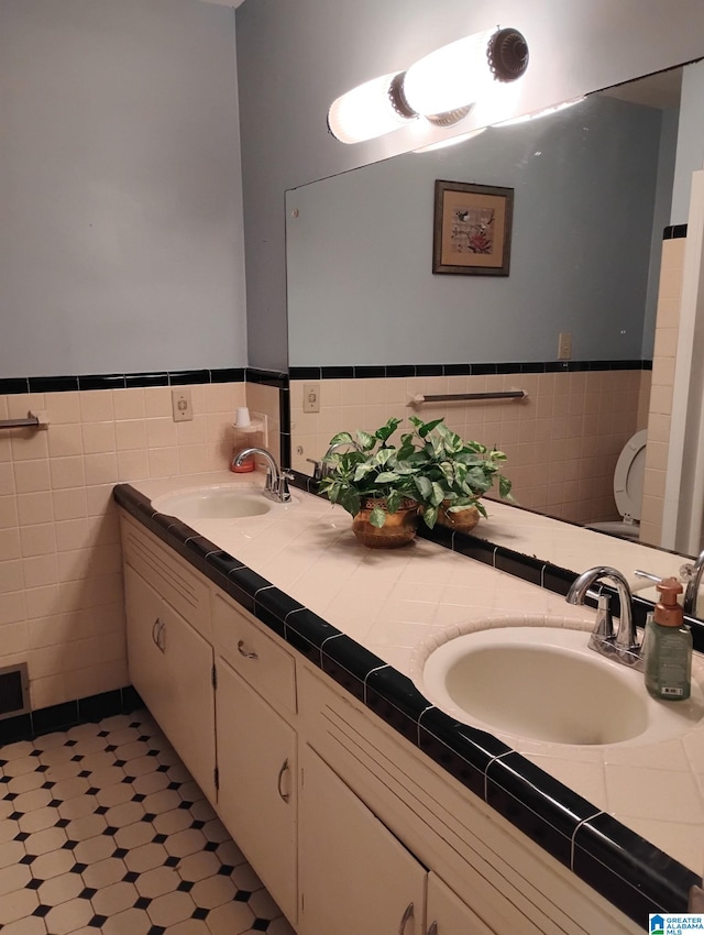 full bathroom with a wainscoted wall, double vanity, and a sink