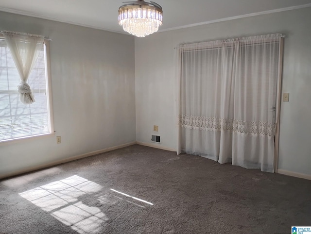 spare room with carpet flooring, visible vents, baseboards, ornamental molding, and an inviting chandelier