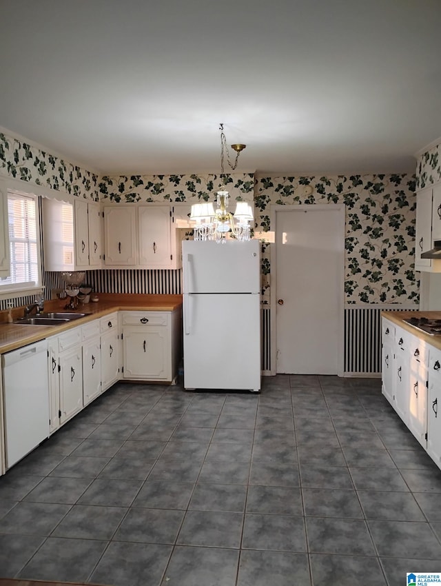 kitchen featuring white appliances, white cabinets, a sink, and wallpapered walls