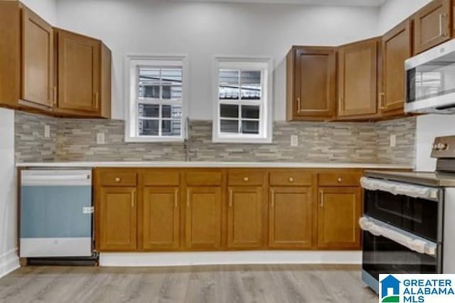 kitchen featuring tasteful backsplash, sink, stainless steel appliances, and light wood-type flooring