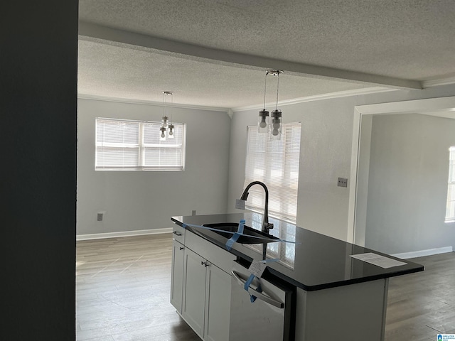 kitchen featuring pendant lighting, sink, an island with sink, white cabinets, and stainless steel dishwasher