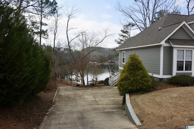 view of home's exterior featuring roof with shingles and a water view