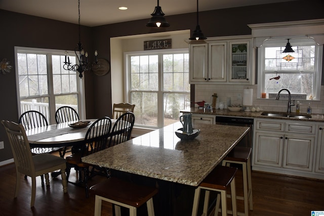 kitchen featuring glass insert cabinets, a breakfast bar, a center island, pendant lighting, and a sink