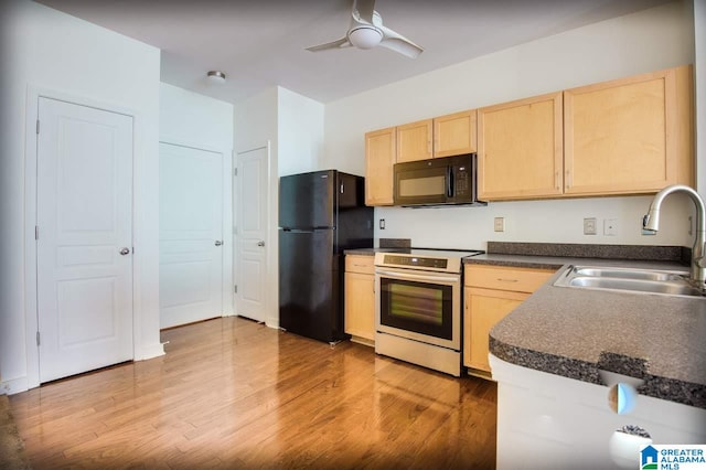 kitchen featuring a sink, dark countertops, black appliances, and light brown cabinetry