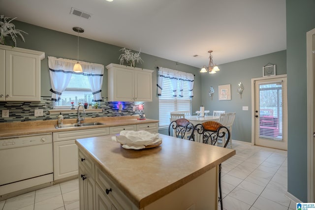 kitchen featuring sink, hanging light fixtures, dishwasher, a kitchen island, and decorative backsplash