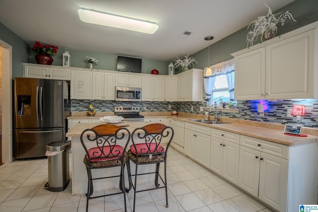 kitchen featuring a kitchen island, appliances with stainless steel finishes, pendant lighting, white cabinetry, and sink