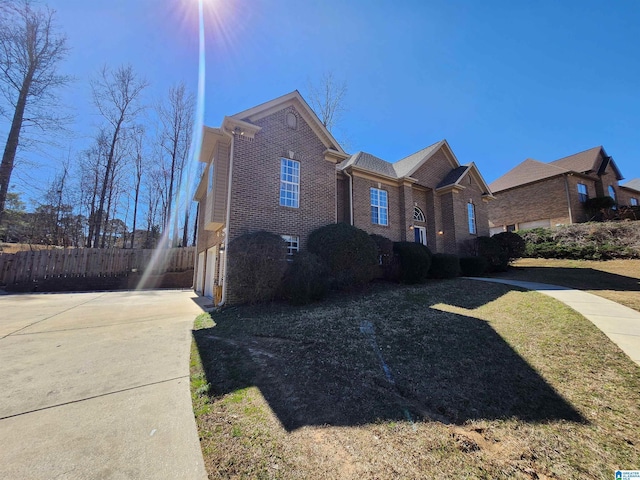 view of property exterior featuring a garage, brick siding, fence, driveway, and a yard