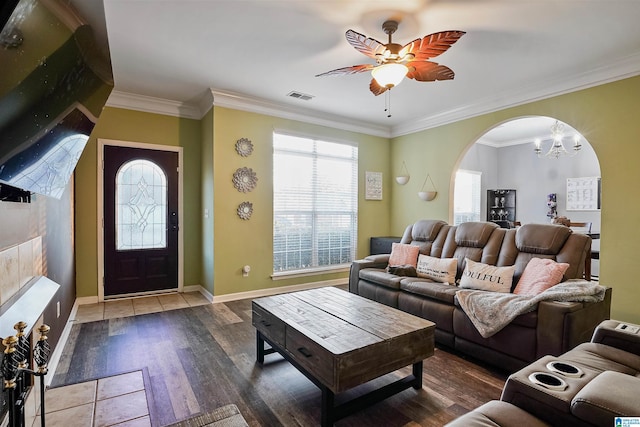 living room with dark hardwood / wood-style flooring, ceiling fan with notable chandelier, and ornamental molding