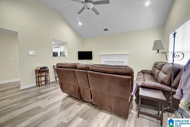 living room with high vaulted ceiling, ceiling fan, and light wood-type flooring