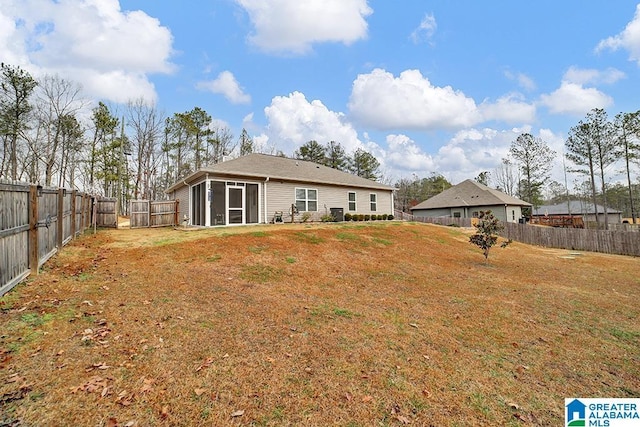 back of property with a lawn and a sunroom