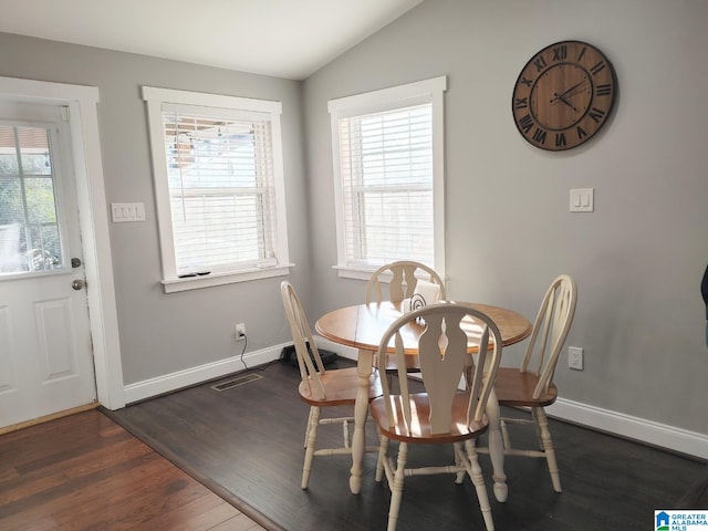 dining space with vaulted ceiling, a healthy amount of sunlight, and dark hardwood / wood-style floors