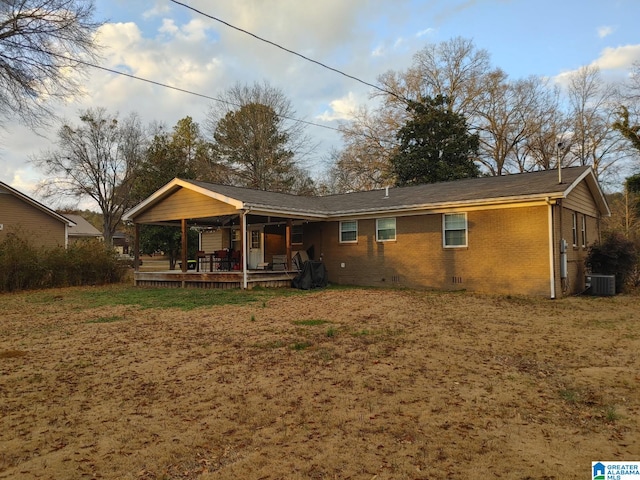 rear view of property featuring central AC and a lawn